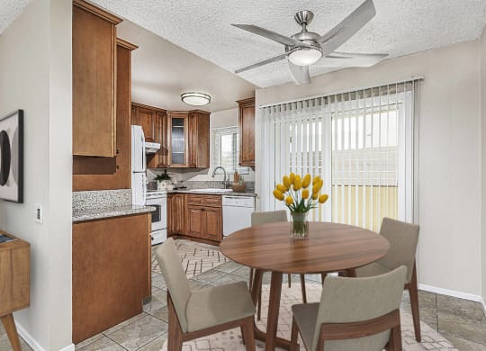 Apartment dining area with a table and four chairs looking out to the private patio. The kitchen is off to the left at Pacific Sands, California, 92117