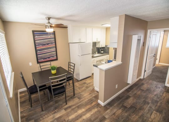 Dining area flows into kitchen and living room. Staged with dining set, couch, table, and plants at Woodland Village Apartments , Woodland, CA