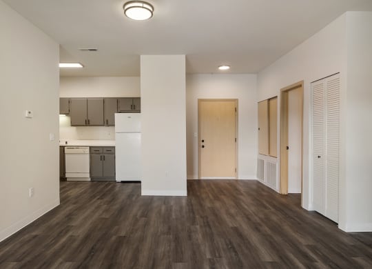 a living room with wood-style flooring, white walls and a kitchen in the background.at Shoreline Village, Washington, 99352