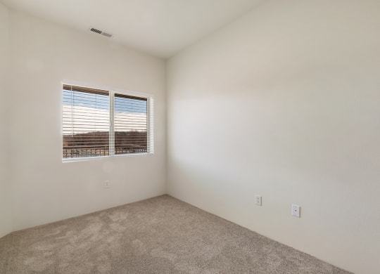 a bedroom with gray carpets, white walls and a sunny window with white blinds.at Shoreline Village, Richland