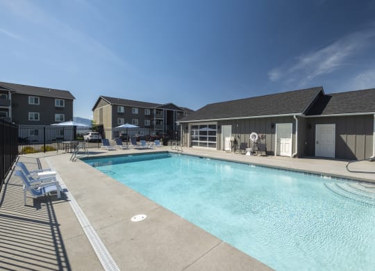 a swimming pool with lounge chairs and umbrellas in front of a building  at Altitude, East Wenatchee
