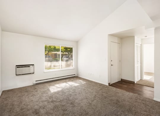 an empty living room with a large window and carpet at Park View Apartments, Wenatchee