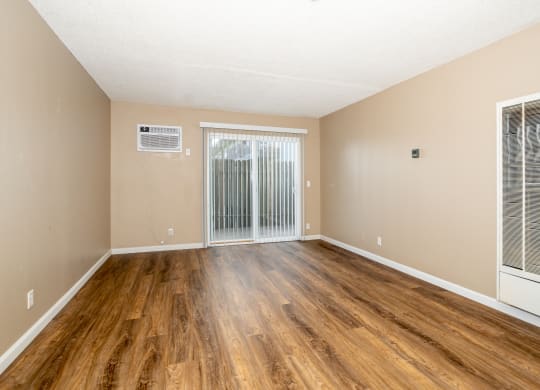 the spacious living room of an apartment with wood flooring and sliding glass doors at Ella 1711 Apartments, Woodland California