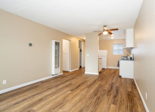 an empty living room with a ceiling fan and a kitchen at Ella 1711 Apartments, Woodland, CA 95695