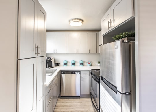 Kitchen in community lounge with stainless steel appliances and new white cabinets at The Lakes Apartments, Moses Lake, WA.