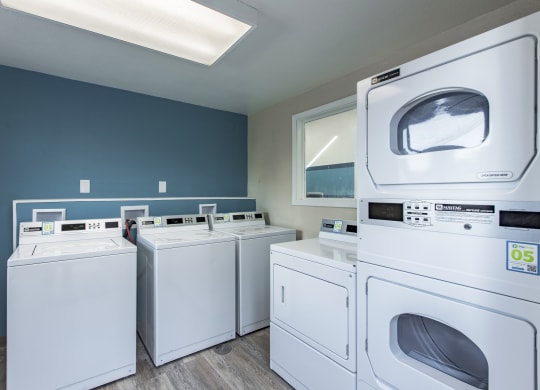 Laundry room showing new white washers and dryers and blue walls at The Lakes Apartments, Moses Lake, WA.