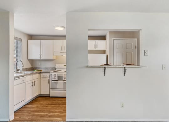 Kitchen divided by a wall with looking window and a small counter. Behind the wall is a pantry door next to a white fridge.at Capitol Crossing, Olympia
