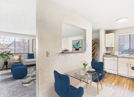 Living room and wood-floor kitchen divided by a textured wall with a looking window and staged with a breakfast table and chairs.at Capitol Crossing, Washington, 98501