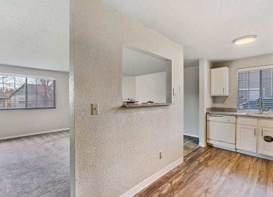 Living room and wood floor kitchen divided by a textured wall, large windows with blinds in living and kitchen area.at Capitol Crossing, Washington