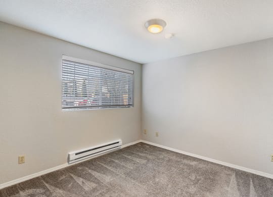 Bedroom with gray carpet, a window on the left wall, a heater below the window, and a light in the center of ceiling.at Capitol Crossing, Washington, 98501