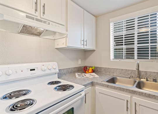 Kitchen corner staged with fruit bowl and hand towels. White stove, range hood, and stainless steel sink.at Capitol Crossing, Washington