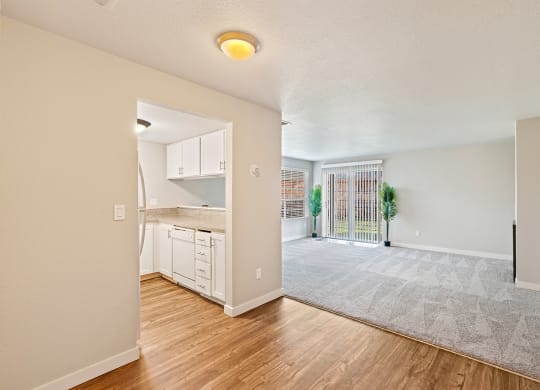 Wood floor kitchen and carpet living room divided by bar counter, sliding glass doors to outside, and window with blinds.at Capitol Crossing, Olympia