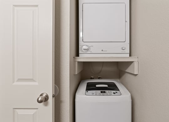 a small laundry room with a washer and dryer and a white door