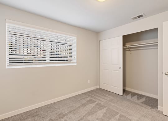 Carpeted bedroom, window with white blinds, and large sliding door closet with closet rod.at Capitol Crossing, Washington, 98501