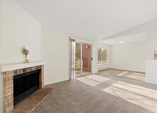 A Pointe East Apartments living room with carpet, a brick fireplace, access to a balcony, and a view of the dining room behind. at Pointe East, Washington, 98424