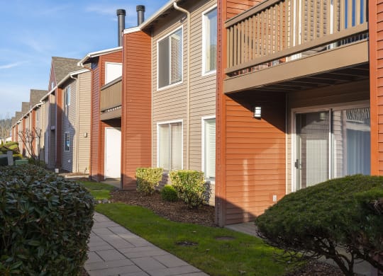 Exterior view of orange and tan apartments with balconies and patios at Pointe East in Fife, WA.