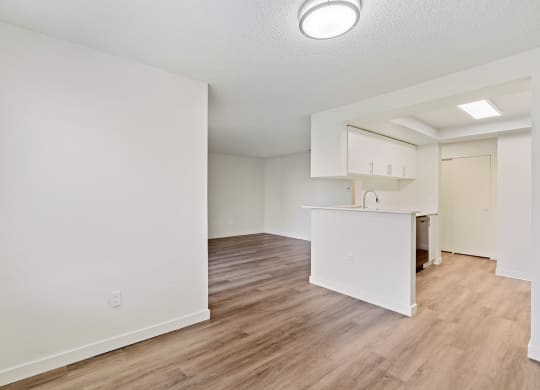 Open layout apartment with wood flooring and white walls at Pointe East Apartments in Fife, WA.