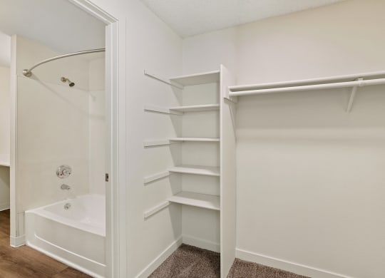 A walk-in closet with custom shelving and access to the bathroom on the left. at Pointe East, Fife, WA, 98424