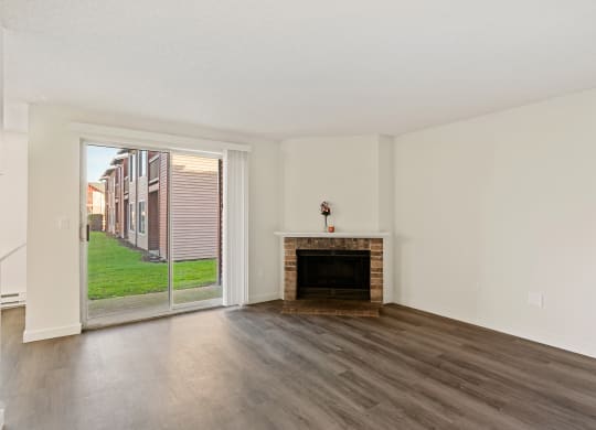 A living room with wood flooring, a brick fireplace and sliding glass doors. at Pointe East, Fife, Washington