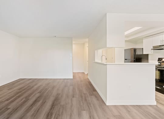 A spacious living room with wood flooring and the kitchen with a large breakfast bar to the right. at Pointe East, Fife, WA, 98424