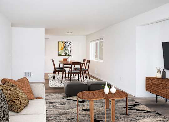 A living room with a white couch, a brown coffee table, and a painting on the wall at our apartments in Renton, WA