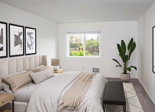 A large bedroom with a potted plant and a large window at our Renton Apartments