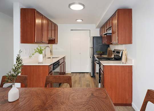 A kitchen with brown wooden cabinets and a white door at Heritage Grove Apartments in Renton, WA
