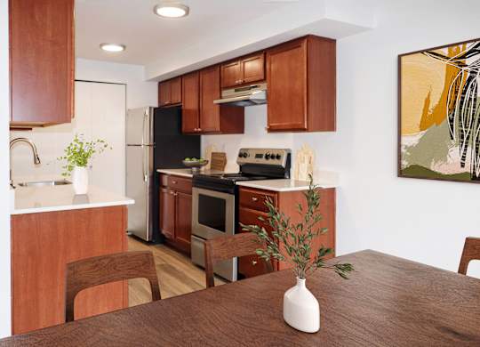 a kitchen with stainless steel appliances and brown wooden cabinets at Heritage Grove Apartments in Renton, WA