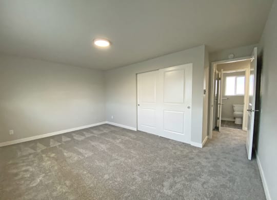 Carpeted bedroom, huge closet at Quilceda Gardens, Washington, 98270  with sliding doors, door to the hallway, and bathroom.