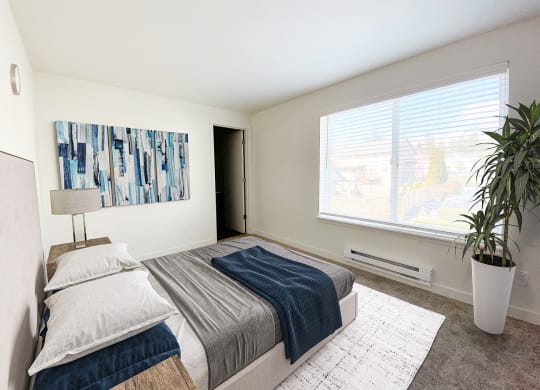 a bedroom with a large window, queen-size bed, and a door on the back wall.at The Trail, Snohomish