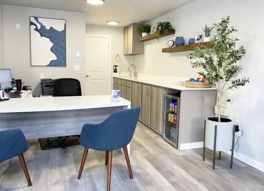 The Trail Apartments lobby office with a l-shaped desk, 2 blue chairs, and a mini fridge with drinks and snacks.at The Trail, Snohomish, WA