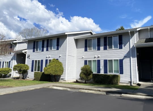 Outside apartments with a paved pathway surrounded by green grass, and well-maintained landscaping.at The Trail, Washington, 98290