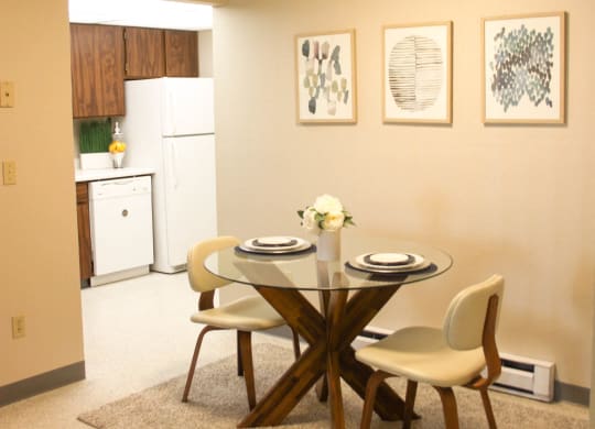 Dining Area that leads into kitchen. Staged with dining table, 2 chairs, wall art and a rug.at The Lakes Apartments, Washington