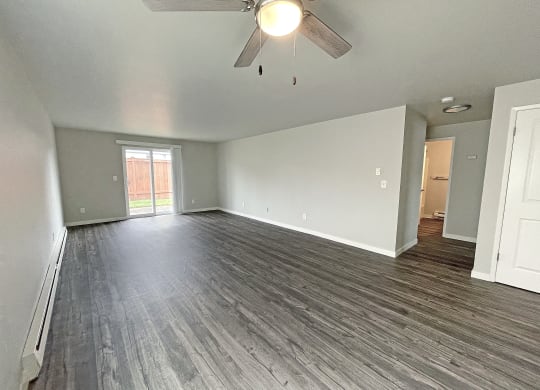 Open layout living room with ceiling fan and sliding glass doors on the back wall to private fenced-in patio.at Quilceda Gardens, Washington, 98270