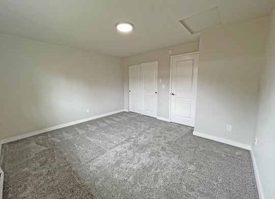 Large carpeted bedroom with double sliding door closet on the back wall next to the bedroom door.at Quilceda Gardens, Marysville, Washington