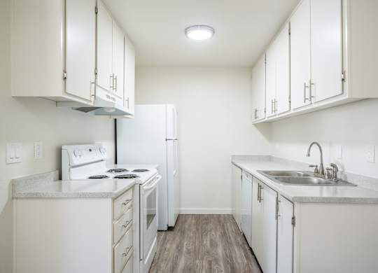 an empty kitchen with white appliances and white cabinets at Kirkwood Meadows Apartments in Pocatello, ID