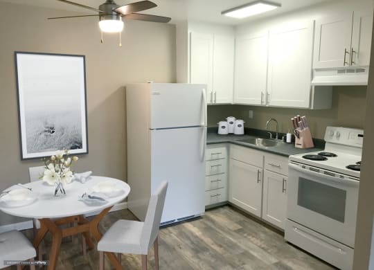 a small kitchen with white appliances and a white table and chairs at Woodland Crossing , Woodland California