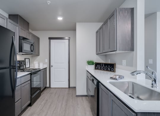 Length perspective of kitchen. with countertops on each side. Pantry door at the end of the kitchen. at Altitude, East Wenatchee, 98802