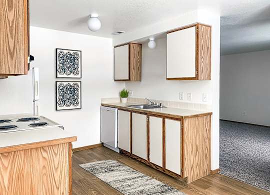 our apartments offer a kitchen with white appliances and wood cabinets at Shiloh Glen, Billings, MT 59102
