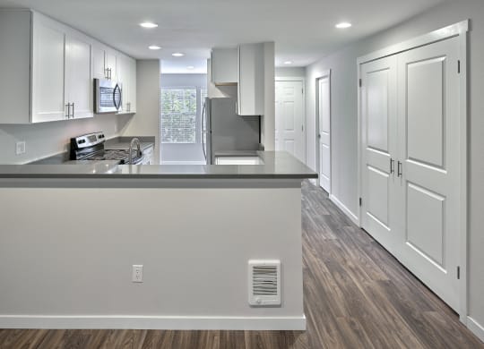 an empty kitchen with white cabinets and a large counter top  at Edmonds Gateway, Edmonds, WA, 98026