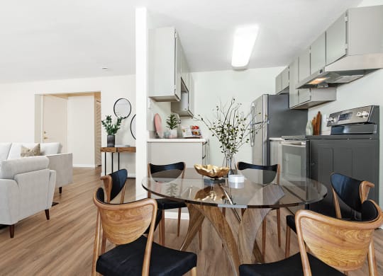 Dining area with glass table surrounded by chairs.  Kitchen and living room visible on either side at University Glen, University Place, WA