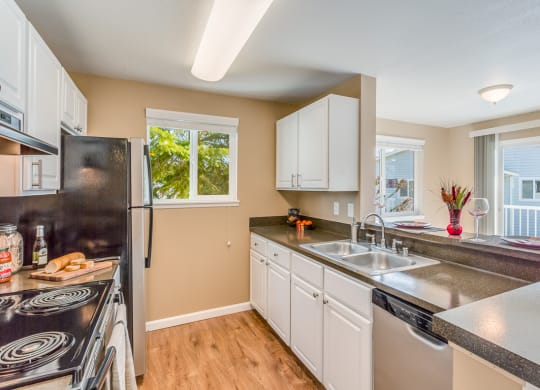 a kitchen with white cabinets and a sink and a refrigerator at Springfield, Renton Washington