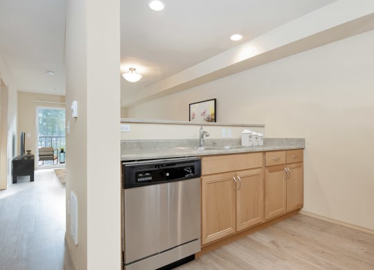 Kitchen area that opens to the living room with a dishwasher, sink, and under sink cabinets at 6 Wood Flats, Lacey