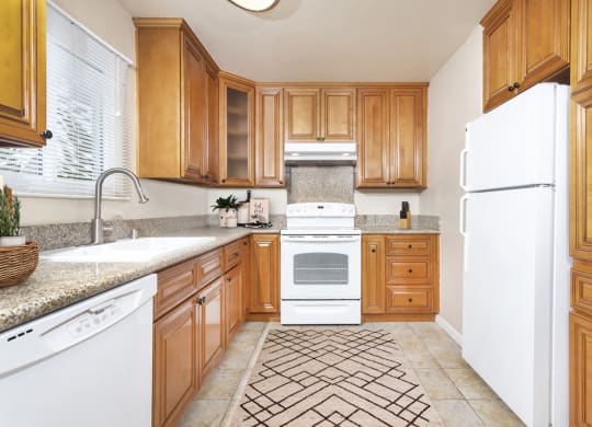 Large U-shaped kitchen with granite countertops, dishwasher, sink, stove, oven and fridge at Pacific Sands, San Diego, California