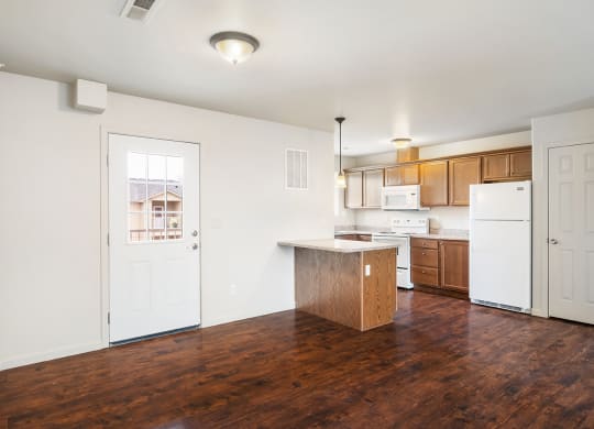 A kitchen with hardwood flooring, a breakfast bar, a microwave, oven, stove top, and full-size fridge. Closet door to the right of the fridge. at Pine Tree Park, Kennewick, 99337