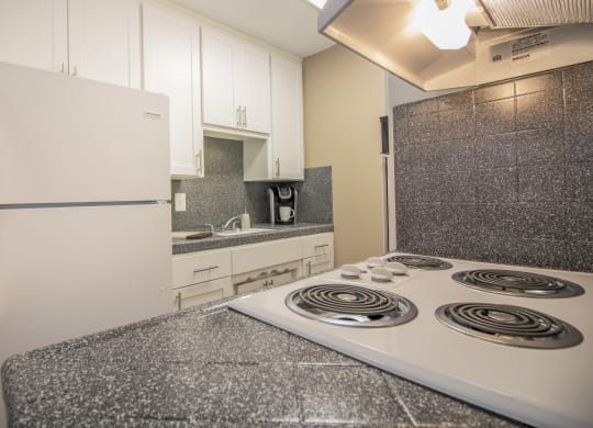 Galley kitchen with new white cabinets and gray faux granite countertops, with dining area visible in the distance  at Woodland Village Apartments , Woodland, CA 95695