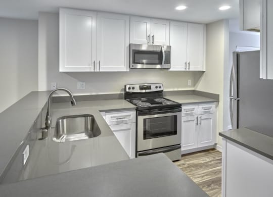 an empty kitchen with white cabinets and stainless steel appliances  at Edmonds Gateway, Washington