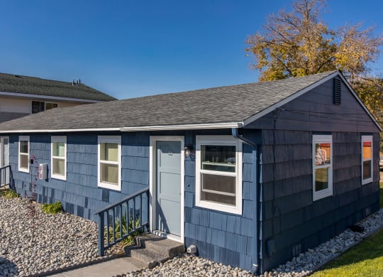 Paved path to the exterior of homes with many windows surrounded by decorative rocks, grass, and landscaping.at The Lakes Apartments, Moses Lake Washington
