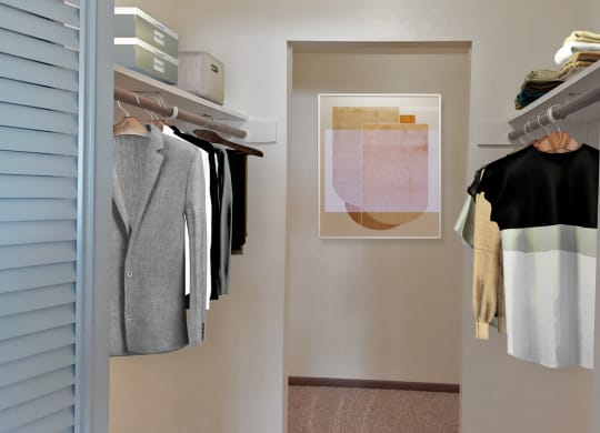 Walk-in closet, carpeted, with shelving, closet rod, staged with clothes on hangers, framed art.at Laurel Park, Twin Falls, ID