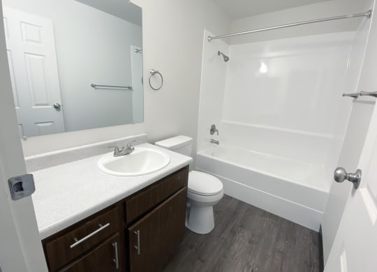 Full bathroom with wood-like flooring, vanity sink, large mirror, toilet, shower, and towel rack.at Laurel Park, Twin Falls, ID